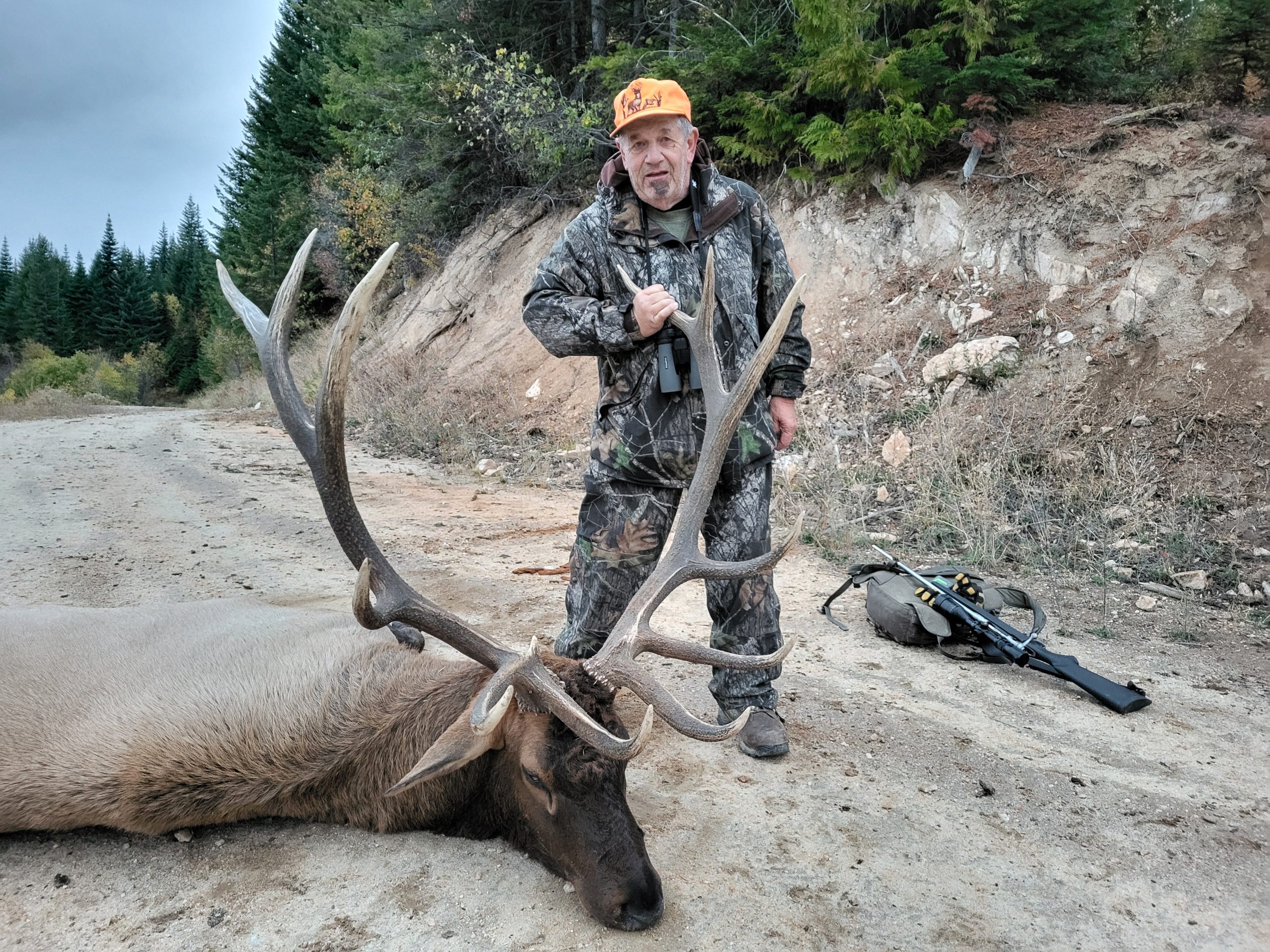 A man stands over a downed buck.