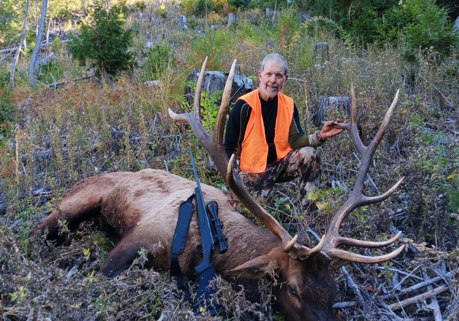 A man crouches over a downed buck.